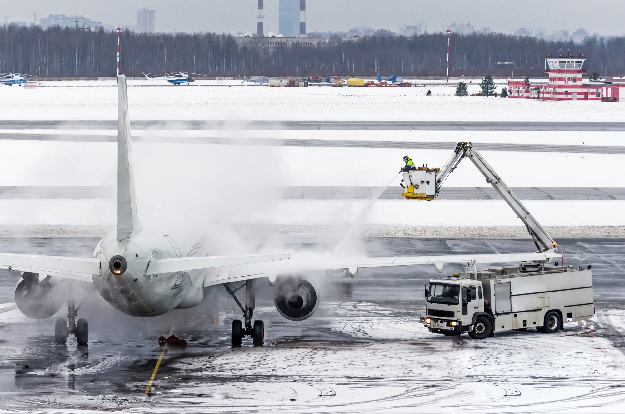 de-icing a plane in winter weather; aircraft on a snowy tarmac being de-iced